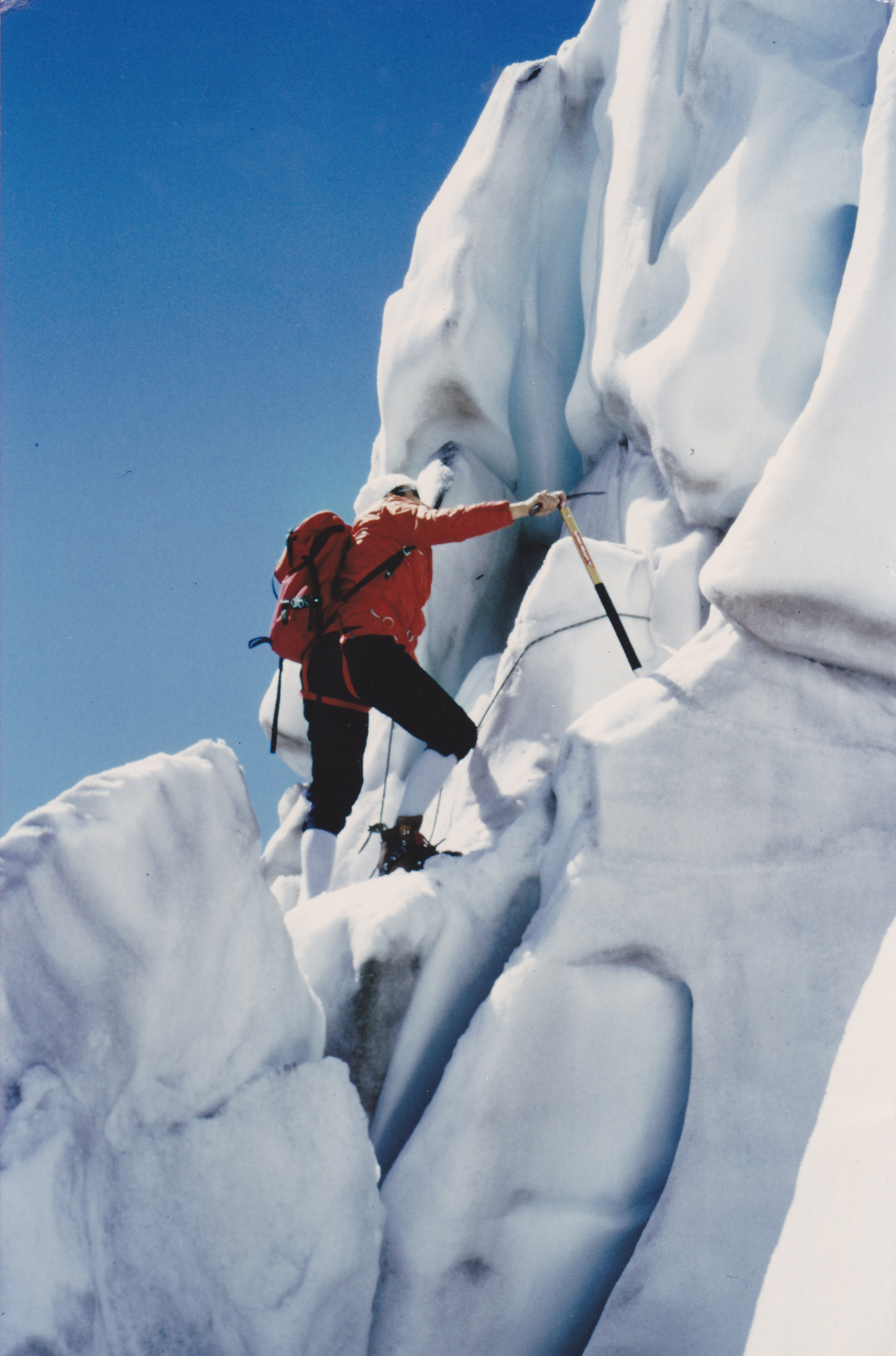An image of a mountaineer climbing up a wall of ice.