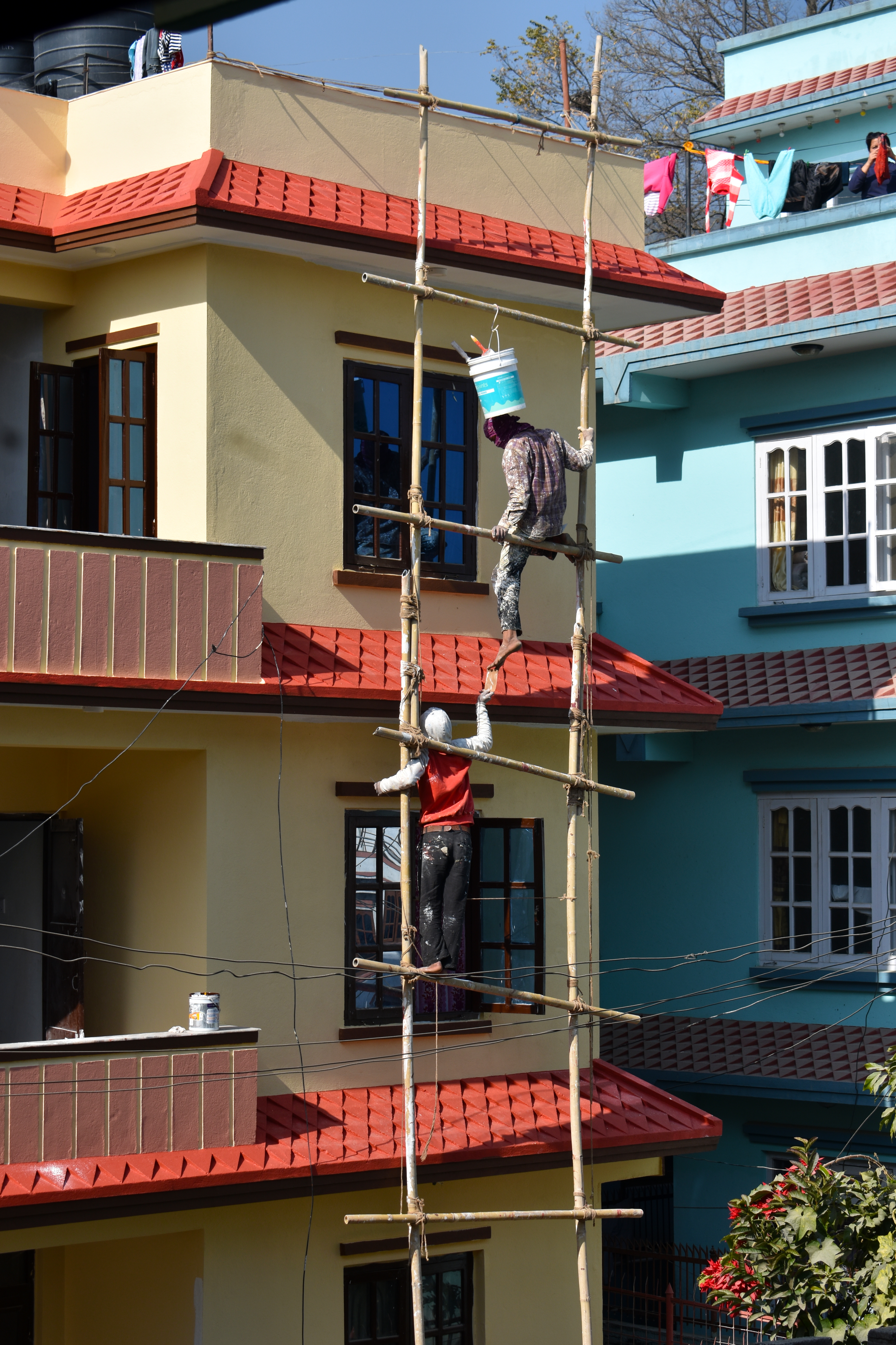 A photo of two people on a ladder. The ladder two vertical posts and 5 visible rungs, running horizontally across.