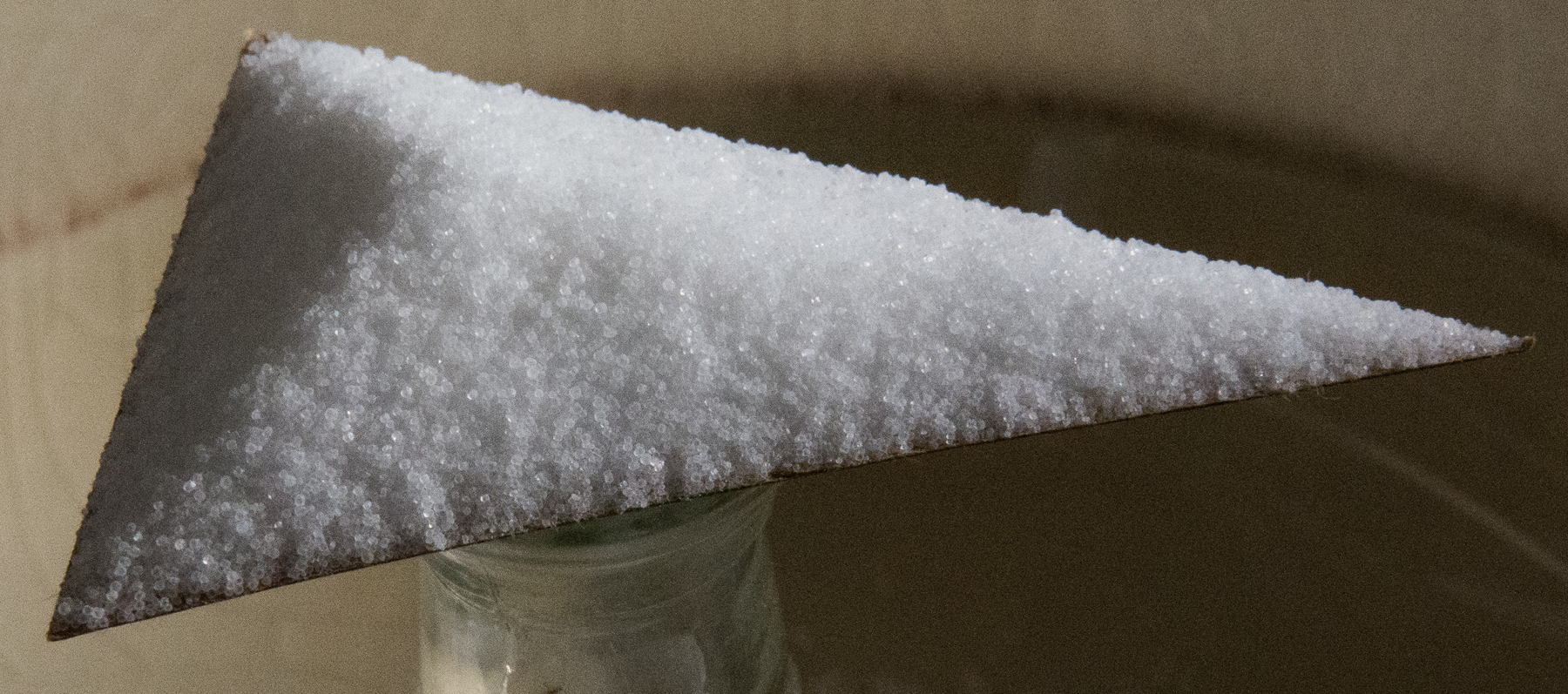 Cardboard triangle on top of glass bottle, with salt on top of entire triangle.