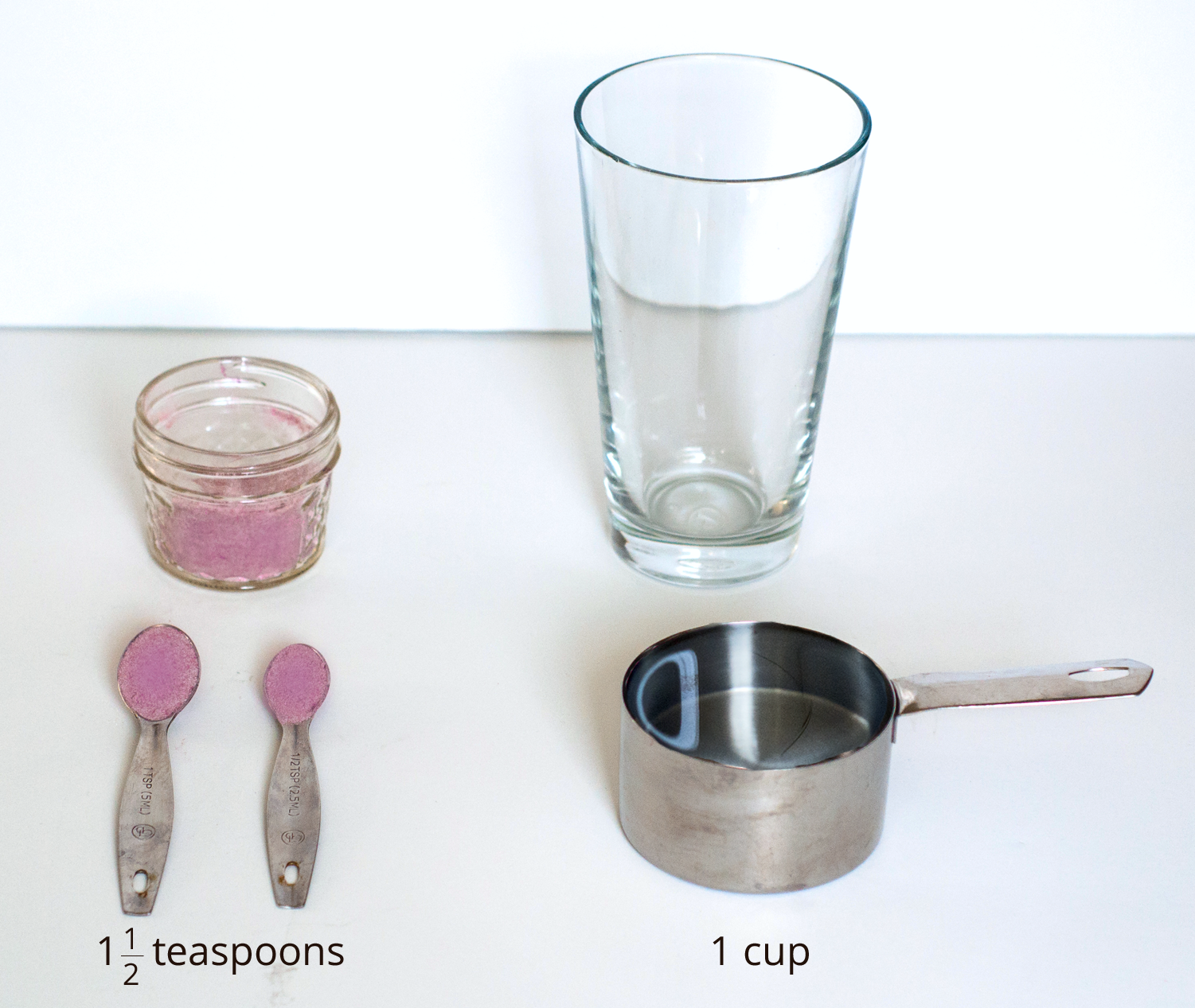 A picture of a glass, drink mixture in a container, one and a half teaspoons of drink mix, and 1 measuring cup.