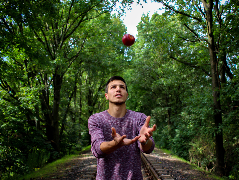 A man tossing an apple up in the air
