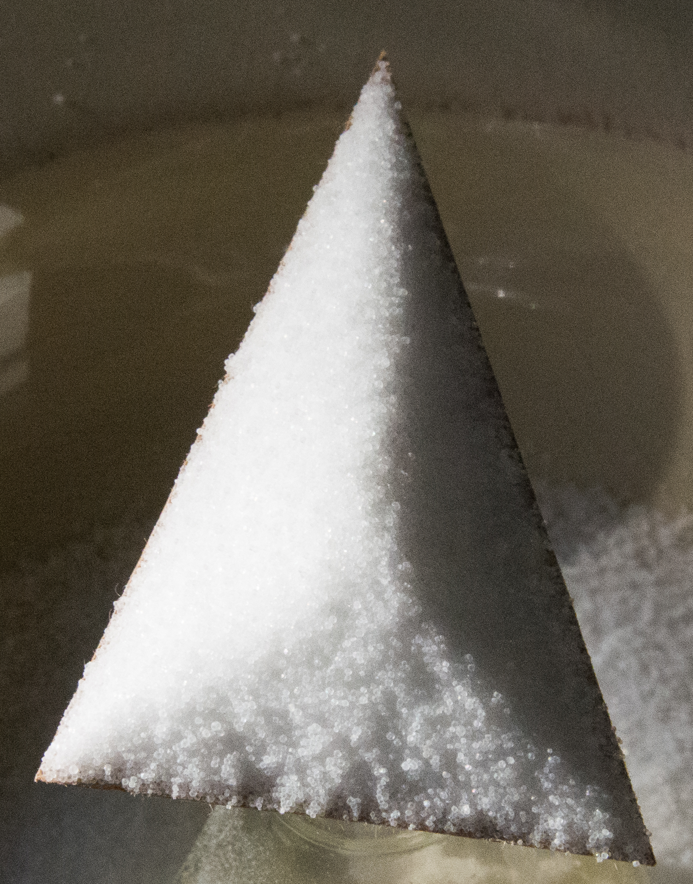 Cardboard triangle on top of glass bottle, with salt on top of entire triangle.