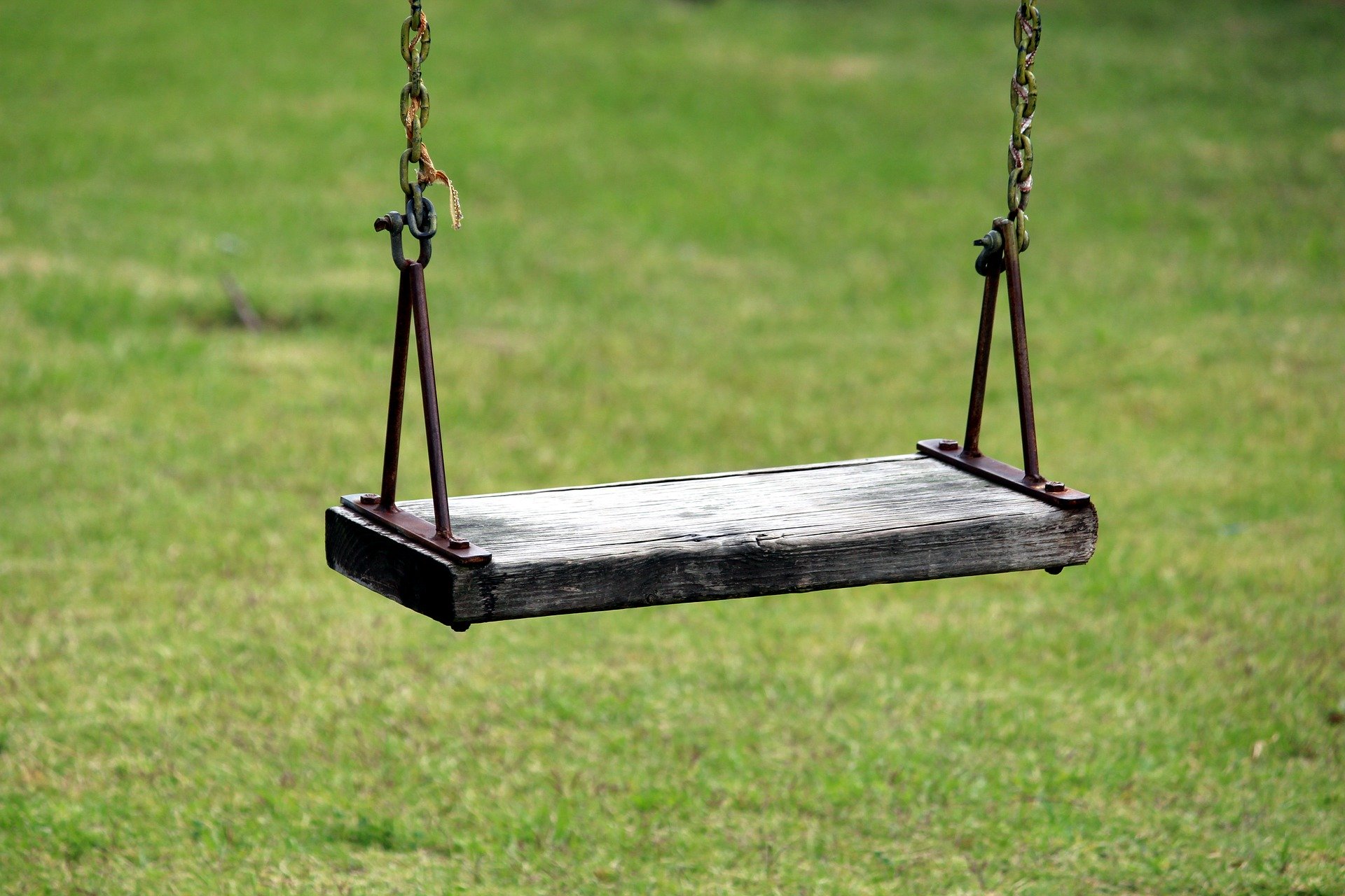 Photograph of a swing. Swing base has 2 sets of parallel sides that meet at right angles. Two three sided shapes at each side of base.