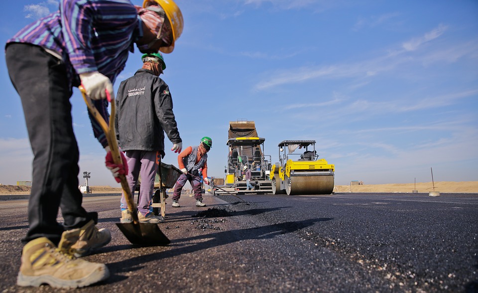 Construction workers laying asphalt.