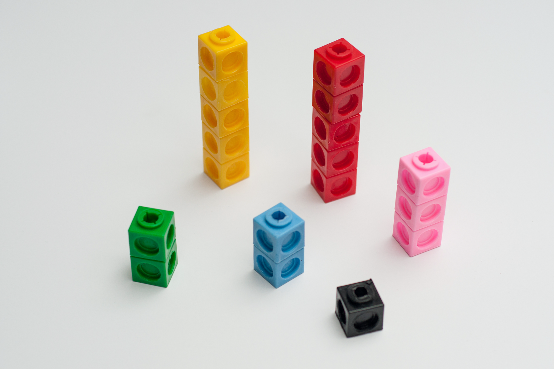 A collection of snap cubes arranged by color. The collection contains 2 green, 5 yellow, 5 red, 3 pink, 2 blue, and 1 black.