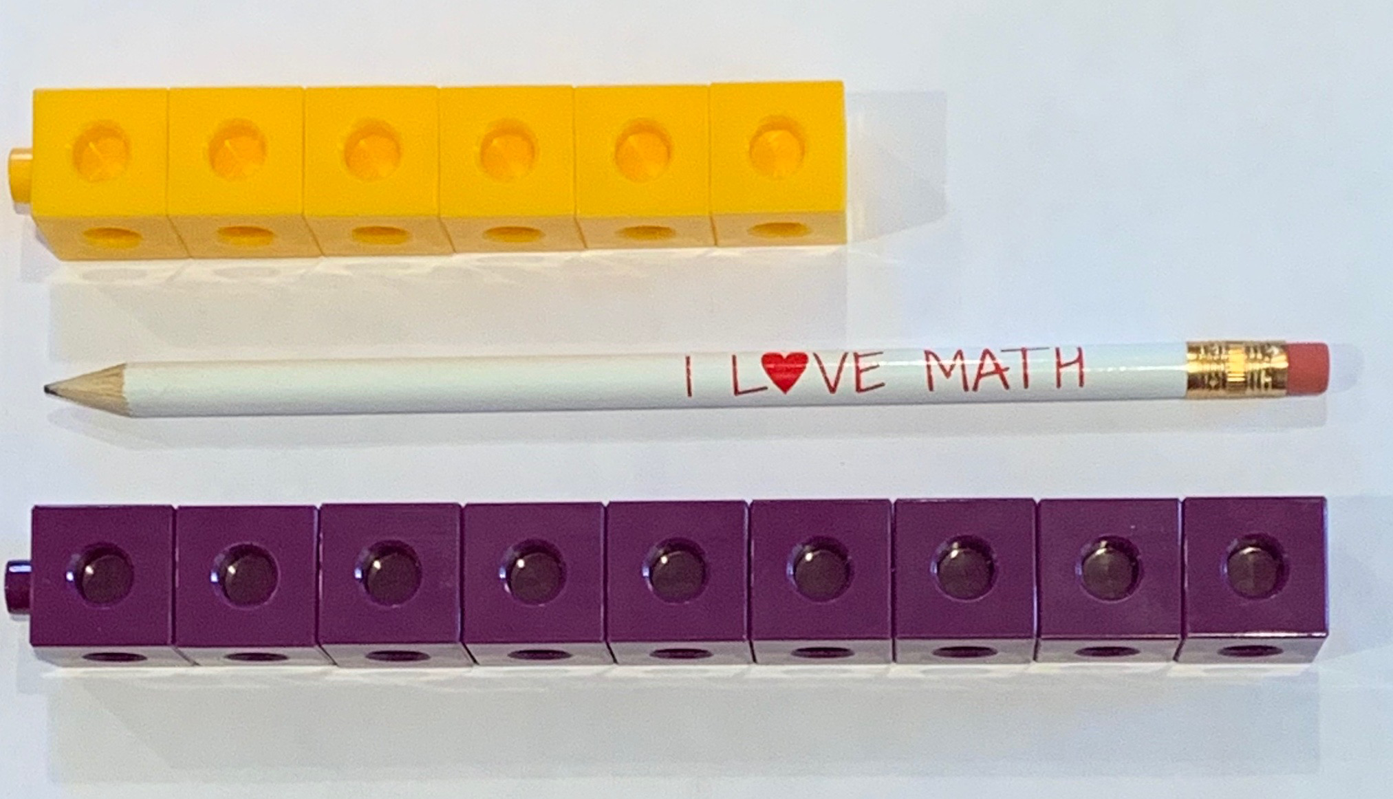3 objects. Yellow tower, 6 connecting cubes. Purple tower, 9 connecting cubes. Pencil, same length as purple tower.